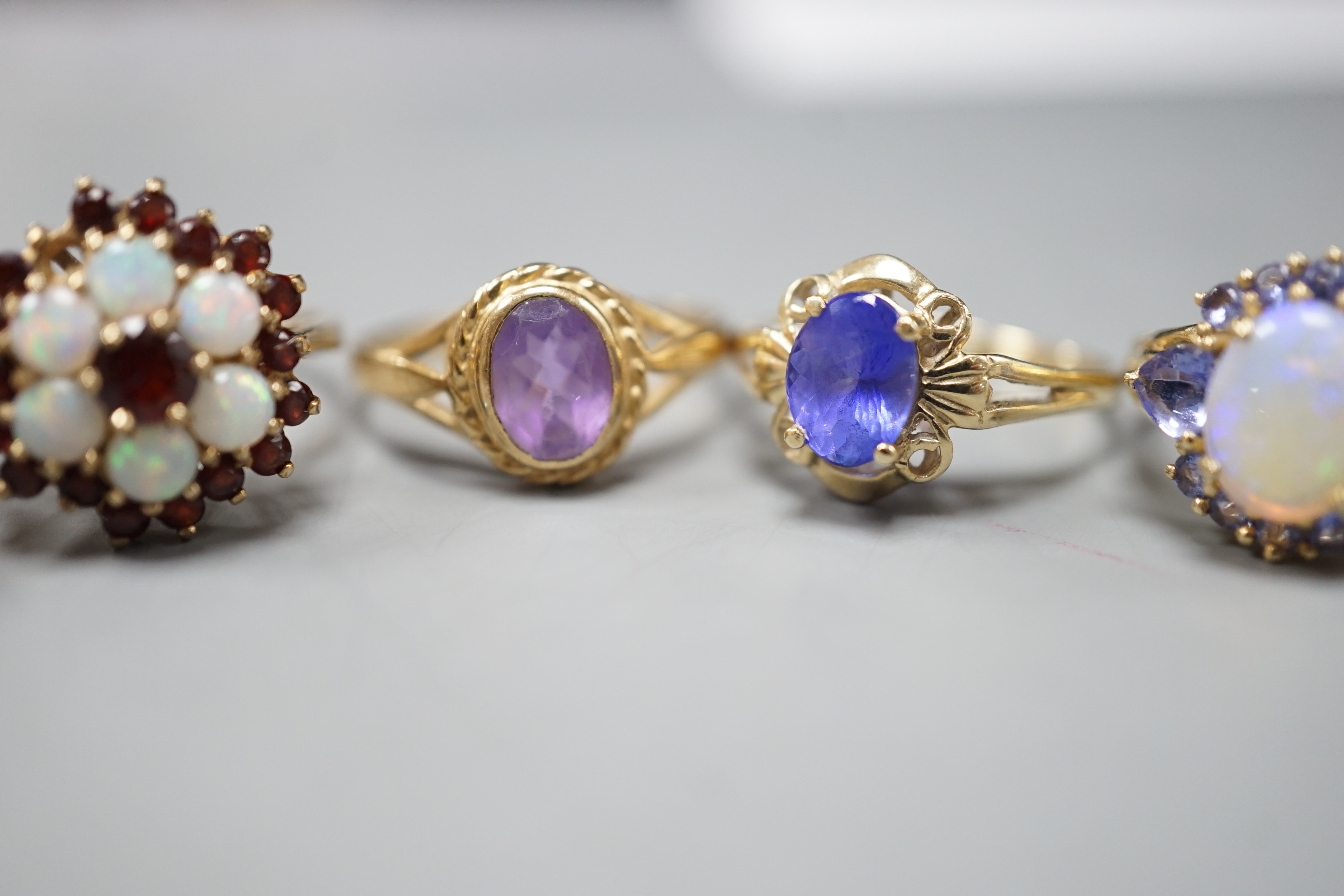 Five assorted modern 9ct gold and gem set dress rings, including, white opal cluster, garnet and white opal cluster and amethyst